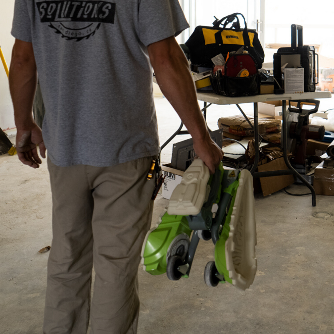 A man is holding Kneel-It in the carrying position as he arrives at a job site.